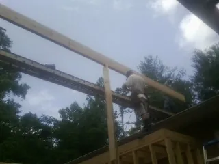 Carpenter setting a ridge beam over a new addition frame — Ice Dam Removal by Roofing Brothers in Alberta