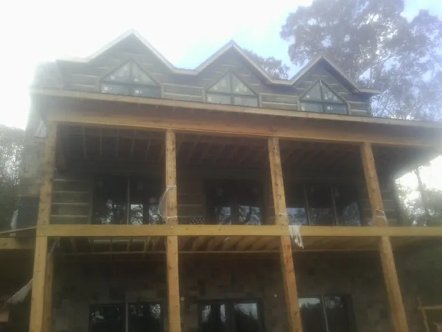 Dormers and porch framing on a large log home under construction — Roof Coating work by our crew in Alberta