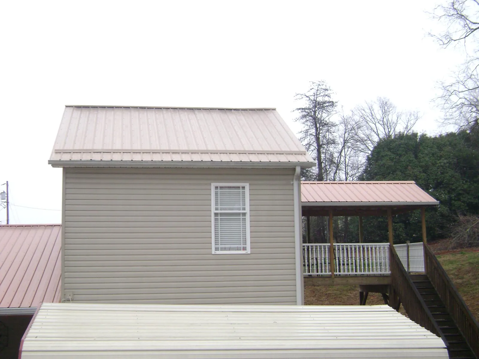 Tan metal roofs on a two story addition and attached porch, from a Roof Replacement job in Alberta