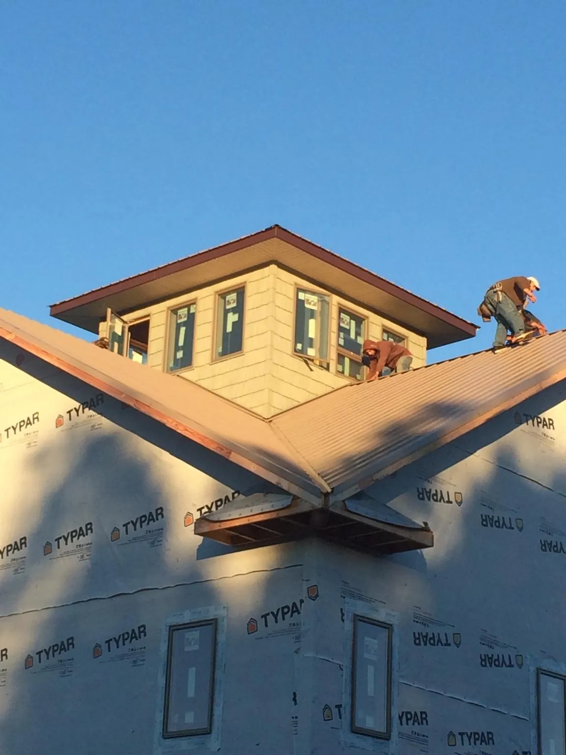 Roofers working around a rooftop cupola on a new metal roof at sunset — Roof Waterproofing in Alberta by Roofing Brothers